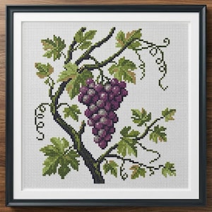 May include: Cross-stitch artwork of a grape vine with a cluster of purple grapes, green leaves, and dark brown branches. The framed piece is set against a white background and framed in a black frame.