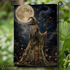 May include: A rectangular garden flag featuring a figure in a long olive green robe and a pointed hat, holding a branch staff. The scene depicts a full moon in a dark, starry night sky with scattered autumn leaves falling around the figure.