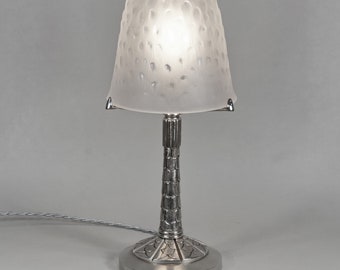 May include: A silver table lamp with a frosted glass shade. The shade has a textured, bumpy surface. The lamp has a round base and a tall, slender stem.