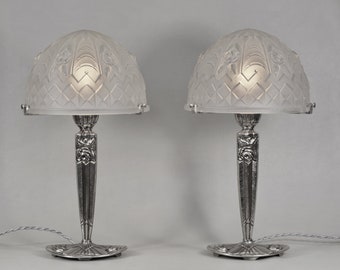 May include: Pair of silver table lamps with frosted glass shades featuring an etched floral design. The lamps have a geometric base and a stem with a floral motif.