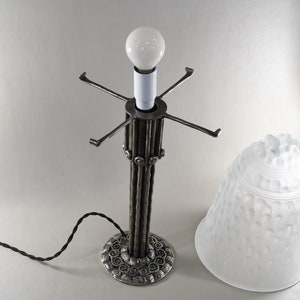 May include: A silver table lamp with a white frosted glass shade. The lamp base is made of twisted metal rods and has a decorative base.