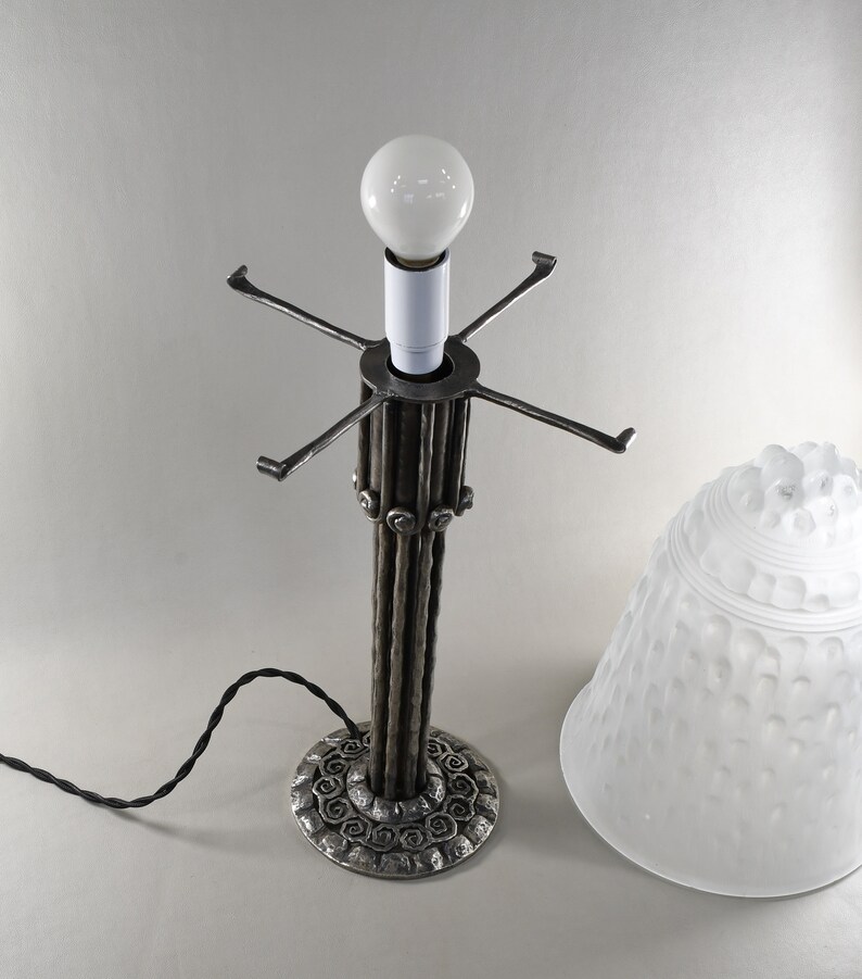 May include: A silver table lamp with a white frosted glass shade. The lamp base is made of twisted metal rods and has a decorative base.