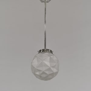 以下が含まれることがあります： 幾何学的なすりガラスのグローブが付いたヴィンテージペンダントライト。グローブはクロム色のロッドと装飾的な天井マウントから吊り下げられています。グローブは多面的なデザインで、ユニークな照明効果を生み出しています。