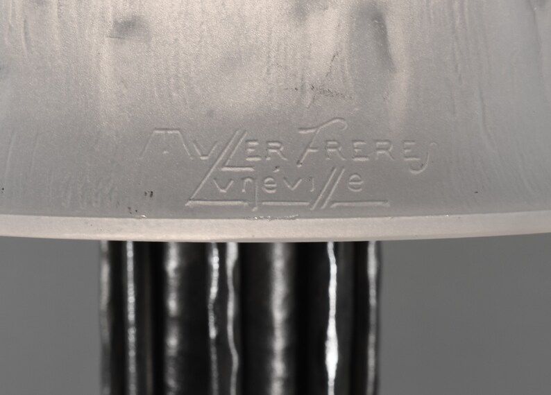 May include: Close-up of a white glass lampshade with the inscription "VER FRERES VREVILE" etched into the bottom.
