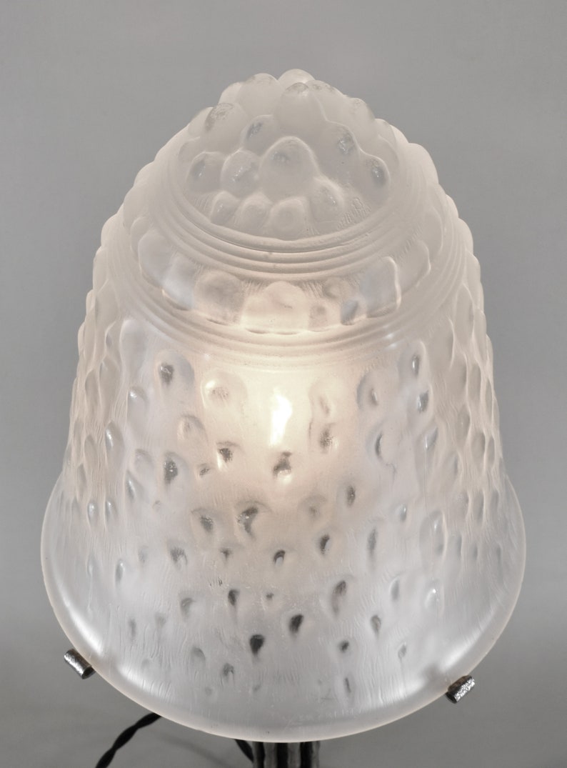 May include: A frosted glass lampshade with a textured, bubble-like design. The shade is white and has a round, bell-shaped form.