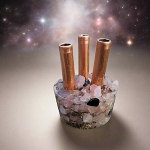 May include: A copper and crystal pen holder with three copper tubes and a base filled with pink and black crystals.