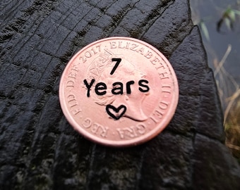 May include: A copper-colored coin with the inscription "2017 ELIZABETH II D.G. REG. F.D." and "7 years" with a heart symbol.