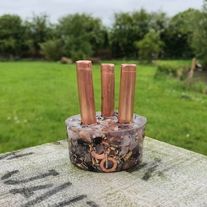 May include: A copper-colored, three-piece incense holder with a clear resin base filled with various crystals and metallic flakes.