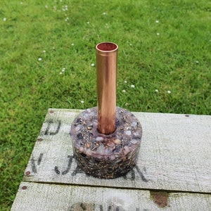 May include: A copper pipe vase with a round base made of gray resin and embedded with small white and gold stones.