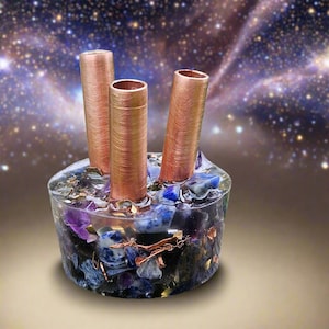 May include: A unique decorative piece featuring three copper tubes rising from a clear resin base. The base is filled with blue and purple stones. The background is a blurred image of a starry night.