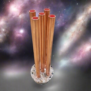 May include: A decorative sculpture featuring six copper tubes with red interiors, rising from a circular base embedded with small, colorful stones. The background is a blurred image of a galaxy.