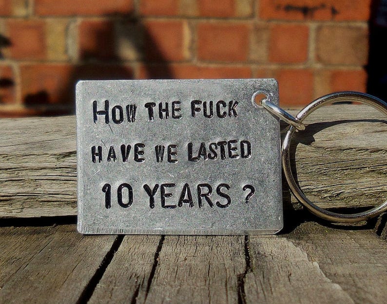 May include: A silver metal keychain with a tag that reads "How the fuck have we lasted 10 years?"