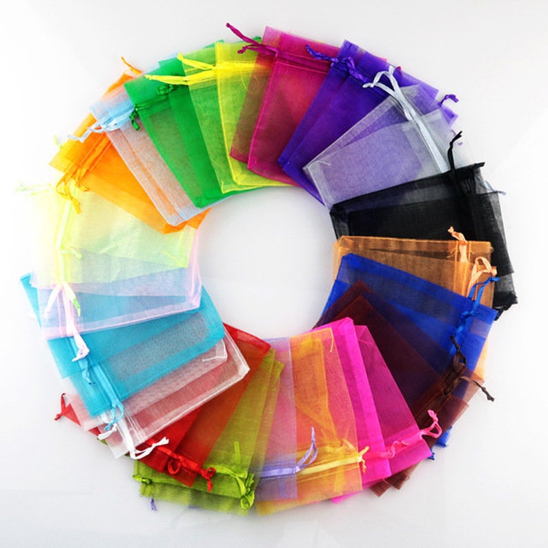 May include: A variety of colorful sheer organza bags with drawstrings. The bags are arranged in a circle, with the drawstrings facing outwards. The bags are made of a lightweight, translucent fabric and are perfect for packaging small gifts or favors.