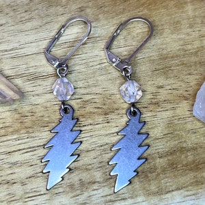 May include: A pair of silver earrings with a lightning bolt charm and a clear crystal bead on each earring.