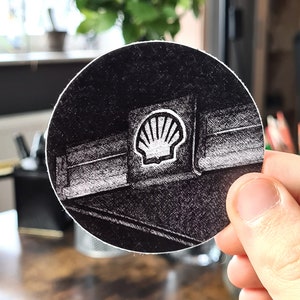 Könnte beinhalten: Eine Schwarzweißzeichnung einer Tankstelle mit dem Shell-Logo an der Seite.