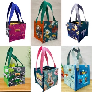 Peut inclure: Six sacs à main en tissu de couleurs différentes avec des motifs et des noms différents. Chaque sac a une forme carrée et est fait d'un tissu doux et durable. Les sacs sont parfaits pour transporter de petits objets comme des livres, des jouets ou des collations.