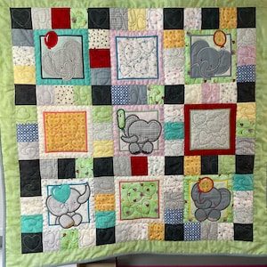 May include: A patchwork quilt with a green border and a variety of colourful squares. Each square features an embroidered elephant with a balloon or ice cream cone. The quilt is made of cotton fabric and is perfect for a baby's nursery.
