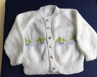White hand knitted  baby cardigan with little sailing ships on. 18-24 months. Soft white washable yarn with knitted boats.