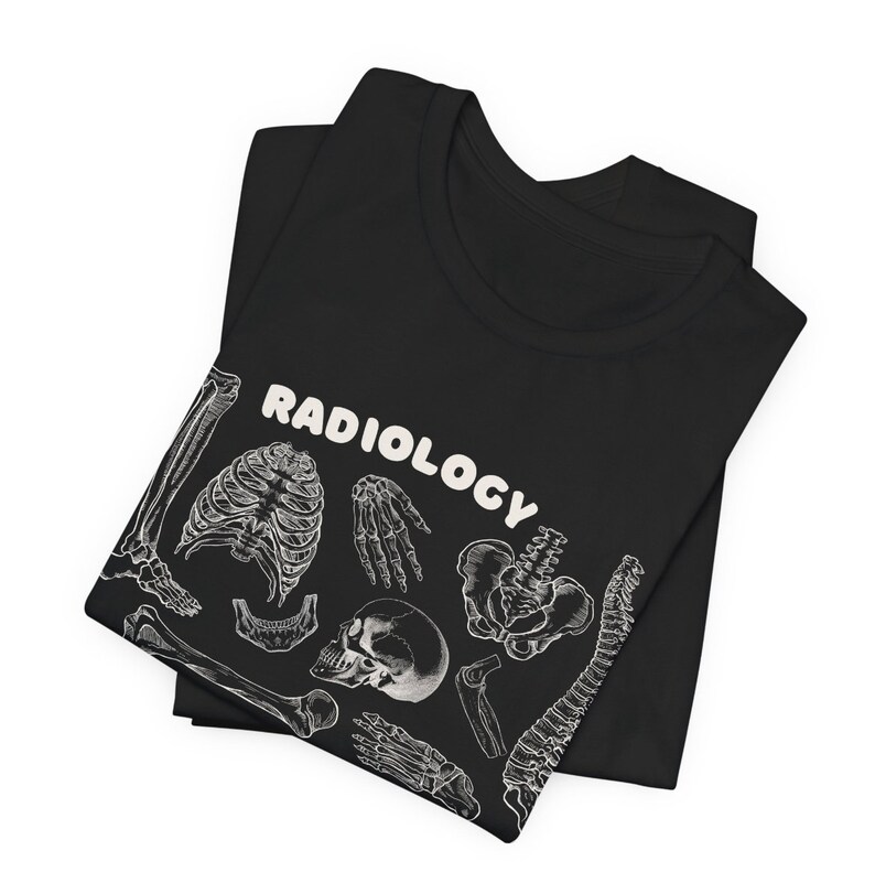 Op de afbeelding: Zwart T-shirt met een witte print van verschillende botten en het woord "RADIOLOGY" in een wit bubbelschrift.