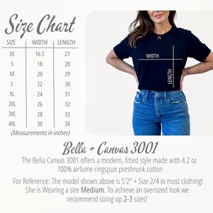 Op de afbeelding: Maattabel voor een zwart Bella + Canvas 3001 T-shirt. De tabel toont de breedte- en lengtemaat in inches voor maten XS tot 4XL. Het model draagt maat M en is 1,57 m lang.