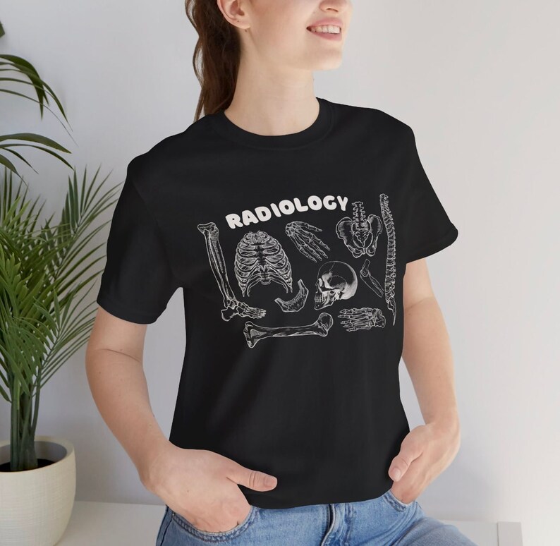 Op de afbeelding: Zwart T-shirt met een witte afbeelding van verschillende botten en het woord "RADIOLOGY" in wit.