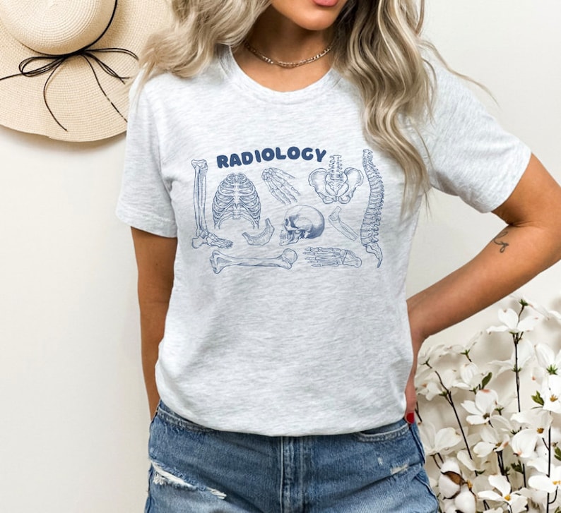 Op de afbeelding: Een grijs T-shirt met een blauwe print van verschillende botten en het woord "RADIOLOGY" op de voorkant.