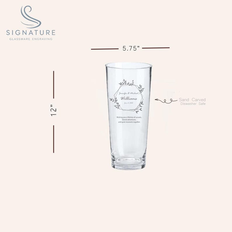 Puede incluir: Un vaso alto y transparente con un grabado personalizado. El vaso mide 30,48 cm de alto y 14,61 cm de ancho. El grabado incluye nombres, una fecha y un dise&ntilde;o floral. El texto dice: "Dese&aacute;ndoles una vida de amor, aventuras compartidas y momentos tranquilos juntos."