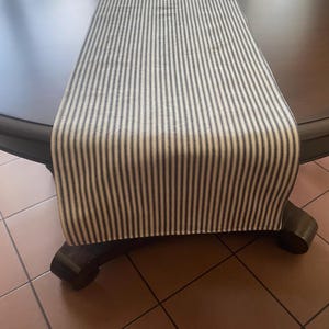 May include: A white and black striped table runner. The runner is made of a woven fabric and has a subtle sheen.