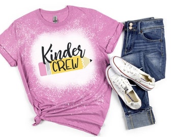 May include: A pink t-shirt with a bleach-splattered design featuring the text "Kinder Crew" and a yellow pencil graphic.