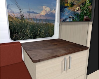May include: Interior view of a recreational vehicle with a built-in seating area and cabinetry. A dark wood countertop sits above a cabinet with two doors and a drawer. A window shows a beach scene, and a TV displays a river view.