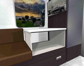 May include: Interior view of a recreational vehicle with a brown sofa, white table, and dark wood cabinetry. A window shows a scenic view of a campground. A flat-screen TV is mounted on the wall, displaying a snowy scene.