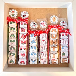 May include: A set of eight wrapped chocolate bars, each with a different letter spelling out the words "GRANDPA", "MOMMY", "AUNTIE", and "UNCLE". Each bar is decorated with a festive Christmas design and a small sticker with a Christmas character.