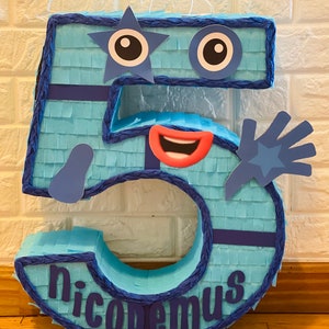May include: A blue and purple number five piñata with a face, a star, and the name "nicodemus" written on it.