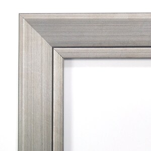 May include: Close-up of the corner of a silver picture frame with a brushed metal finish.