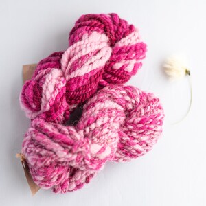 Roze en glanzend ombre handgesponnen kunstgaren voor weven, textiel en vezelkunst.