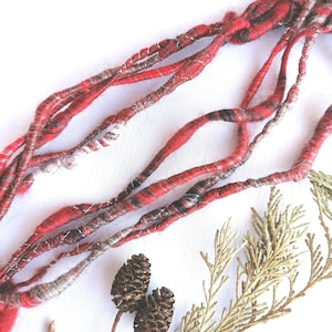 Rot, schwarz und silber handgesponnenes Kunstgarn zum Weben, Textil- und Faserhandwerk.