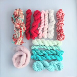 May include: A collection of yarn skeins and a bundle of roving wool in various colours including red, white, pink, turquoise, and mint green. The assortment features solid colours, variegated blends, and twisted red and white striped yarn textures.
