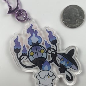 Pu&ograve; includere: Un portachiavi in acrilico trasparente con tre personaggi Pok&eacute;mon: Chandelure, Litwick e Lampent. Chandelure &egrave; un Pok&eacute;mon di tipo fantasma viola e nero con una grande testa rotonda e quattro braccia. Litwick &egrave; un piccolo Pok&eacute;mon di tipo fantasma bianco con una fiamma blu sulla testa. Lampent &egrave; un piccolo Pok&eacute;mon di tipo fantasma nero con una fiamma blu sulla testa e un cappello viola.