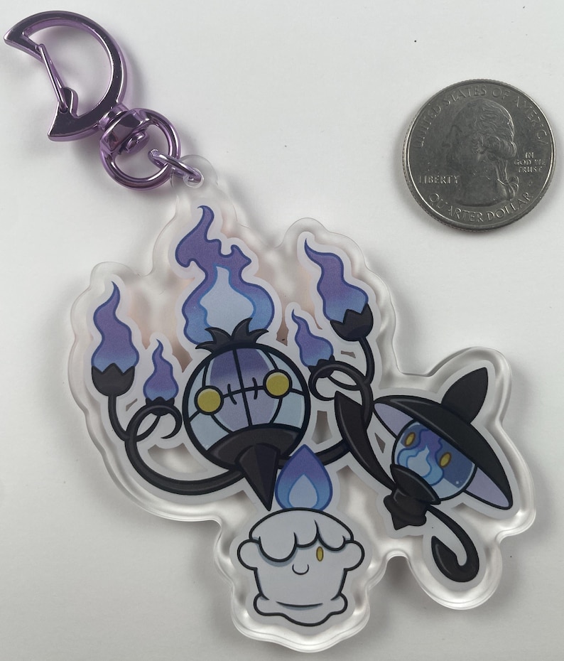 Pu&ograve; includere: Un portachiavi in acrilico trasparente con tre personaggi Pok&eacute;mon: Chandelure, Litwick e Lampent. Chandelure &egrave; un Pok&eacute;mon di tipo fantasma viola e nero con una grande testa rotonda e quattro braccia. Litwick &egrave; un piccolo Pok&eacute;mon di tipo fantasma bianco con una fiamma blu sulla testa. Lampent &egrave; un piccolo Pok&eacute;mon di tipo fantasma nero con una fiamma blu sulla testa e un cappello viola.