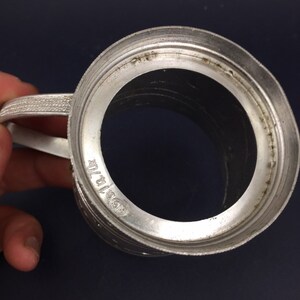 Peut inclure: Une tasse en m&eacute;tal argent&eacute; avec une anse et une base circulaire. La tasse a un bord sur&eacute;lev&eacute; et une surface lisse et polie. Le fond de la tasse porte l'inscription "0.5 ltr."