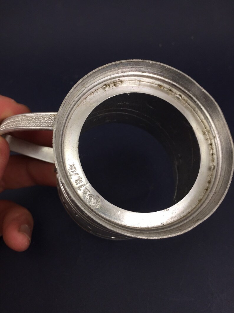 Peut inclure: Une tasse en m&eacute;tal argent&eacute; avec une anse et une base circulaire. La tasse a un bord sur&eacute;lev&eacute; et une surface lisse et polie. Le fond de la tasse porte l'inscription "0.5 ltr."