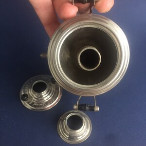 Puede incluir: Una bocina de gram&oacute;fono plateada vintage con un asa negra y dos piezas m&aacute;s peque&ntilde;as a juego. La bocina tiene una abertura ancha y acampanada y una base estrecha. Las piezas est&aacute;n sobre una superficie azul.