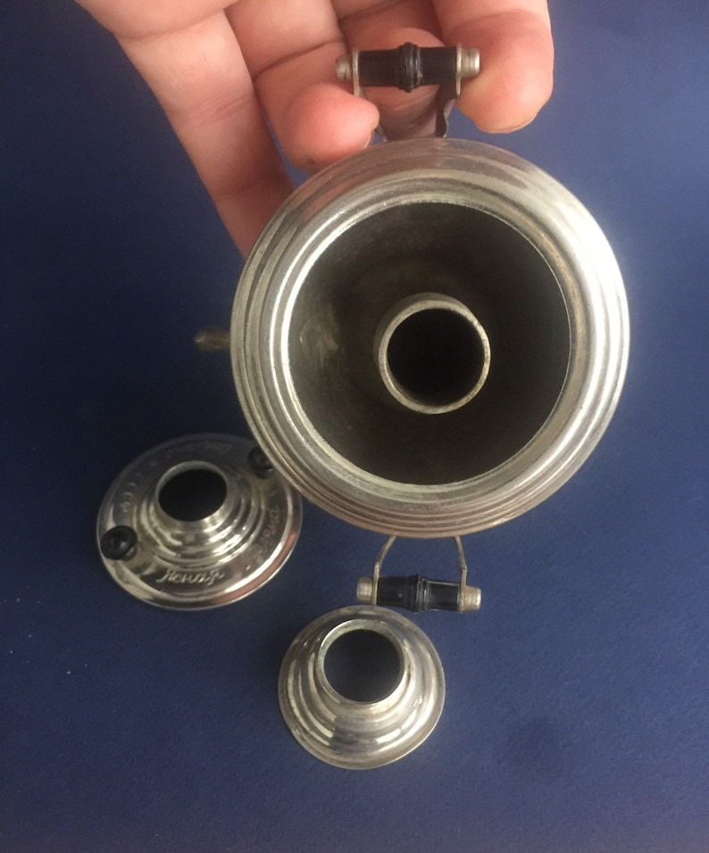 Puede incluir: Una bocina de gram&oacute;fono plateada vintage con un asa negra y dos piezas m&aacute;s peque&ntilde;as a juego. La bocina tiene una abertura ancha y acampanada y una base estrecha. Las piezas est&aacute;n sobre una superficie azul.