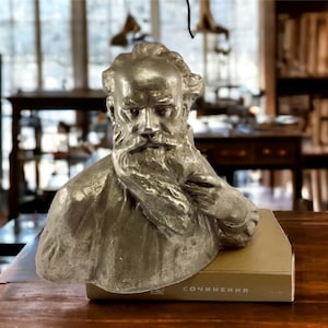 May include: A silver bust of a man with a beard, sitting on a book with the word "СОЧИНЕНИЯ" printed on the cover.