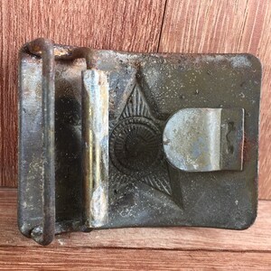 Pu&ograve; includere: Una fibbia per cintura in metallo vintage con un design a stella e una finitura usurata e invecchiata.