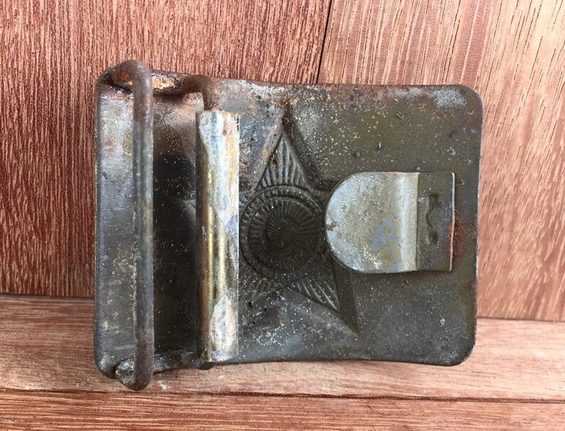 Pu&ograve; includere: Una fibbia per cintura in metallo vintage con un design a stella e una finitura usurata e invecchiata.