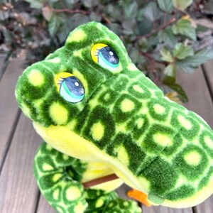 May include: Green and yellow plush alligator toy with large, round eyes. The alligator has a textured, spotted pattern.