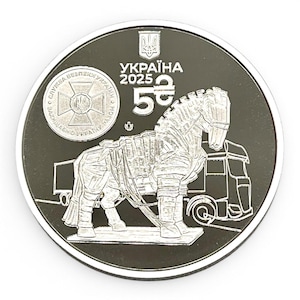 Może przedstawiać: Srebrna moneta z motywem konia trojańskiego, ciężarówki i napisem "УКРАЇНА 2025 5". Moneta przedstawia szczegółową ilustrację konia i ciężarówki, z dodatkowym tekstem i herbem w górnej części. Moneta jest okrągła ze srebrnym obramowaniem.