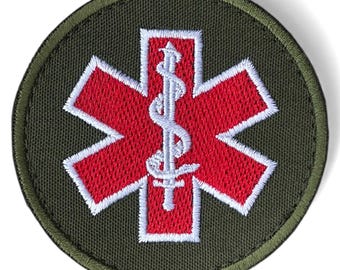 May include: Round embroidered patch featuring a red Star of Life emblem with a white staff and snake symbol at the center. The star is outlined in white, set against a dark green background with a matching border.