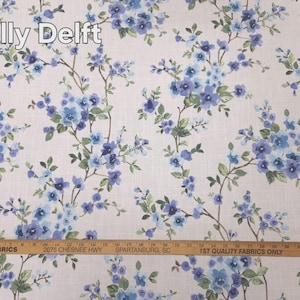 May include: Floral fabric with a white background and a pattern of blue flowers and green leaves. The text "Molly Delft" is at the top. A ruler is at the bottom with the text "MARTHA'S FABRICS".